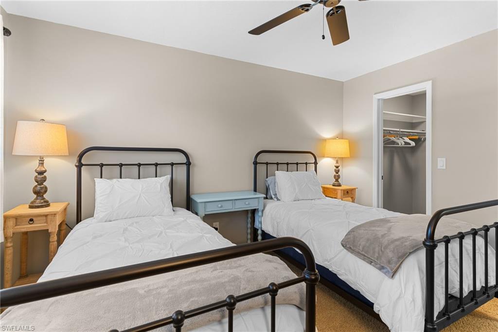 Carpeted bedroom with a spacious closet and a ceiling fan