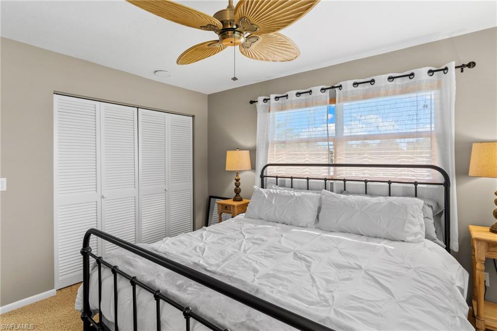 Bedroom with a closet, ceiling fan, and light carpet