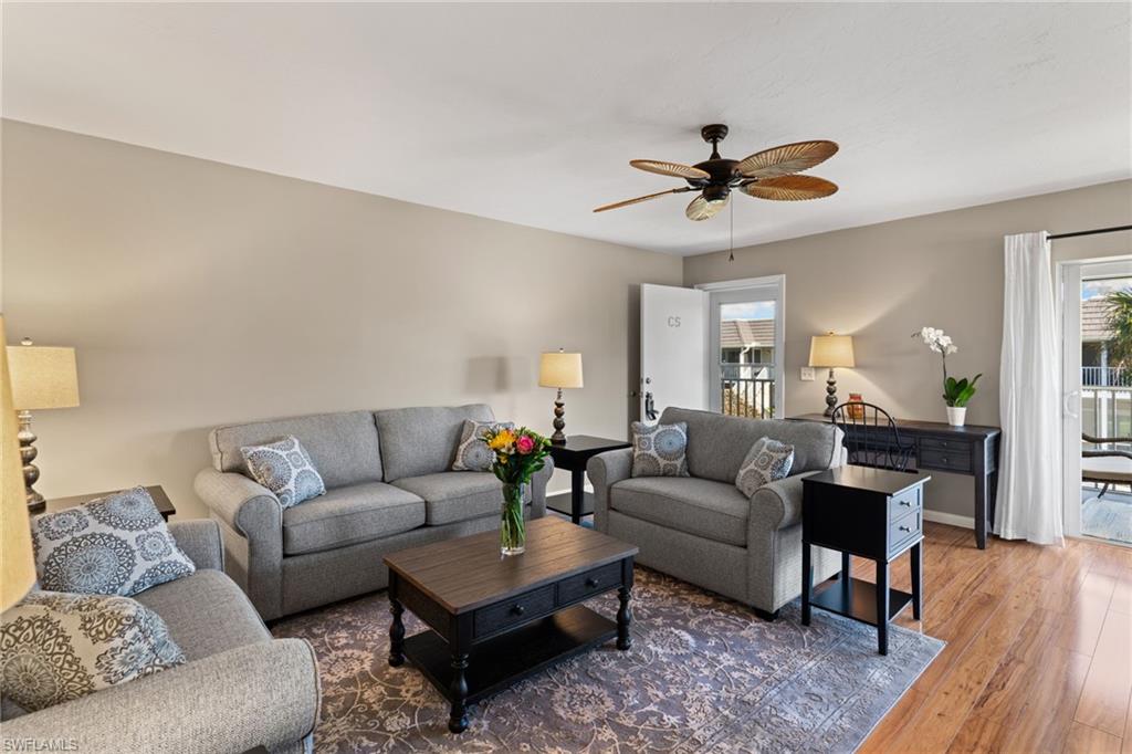Living room with wood-type flooring, ceiling fan, and healthy amount of natural light