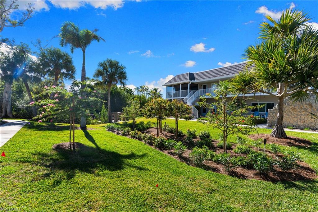 View of green lawn featuring a balcony and stairway