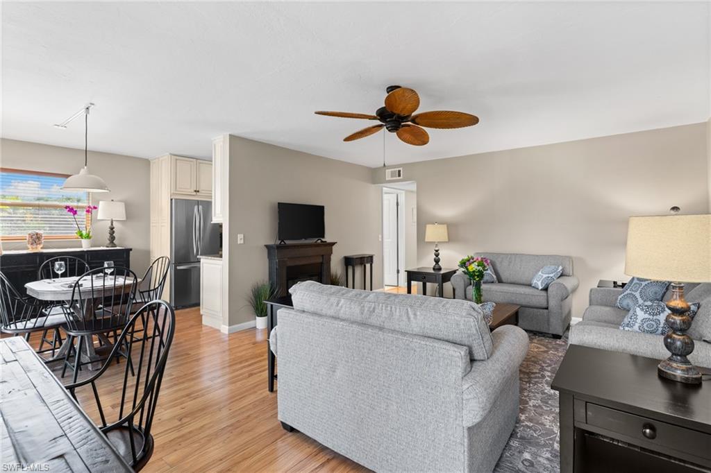 Living area with light wood-style floors, a fireplace, and a ceiling fan