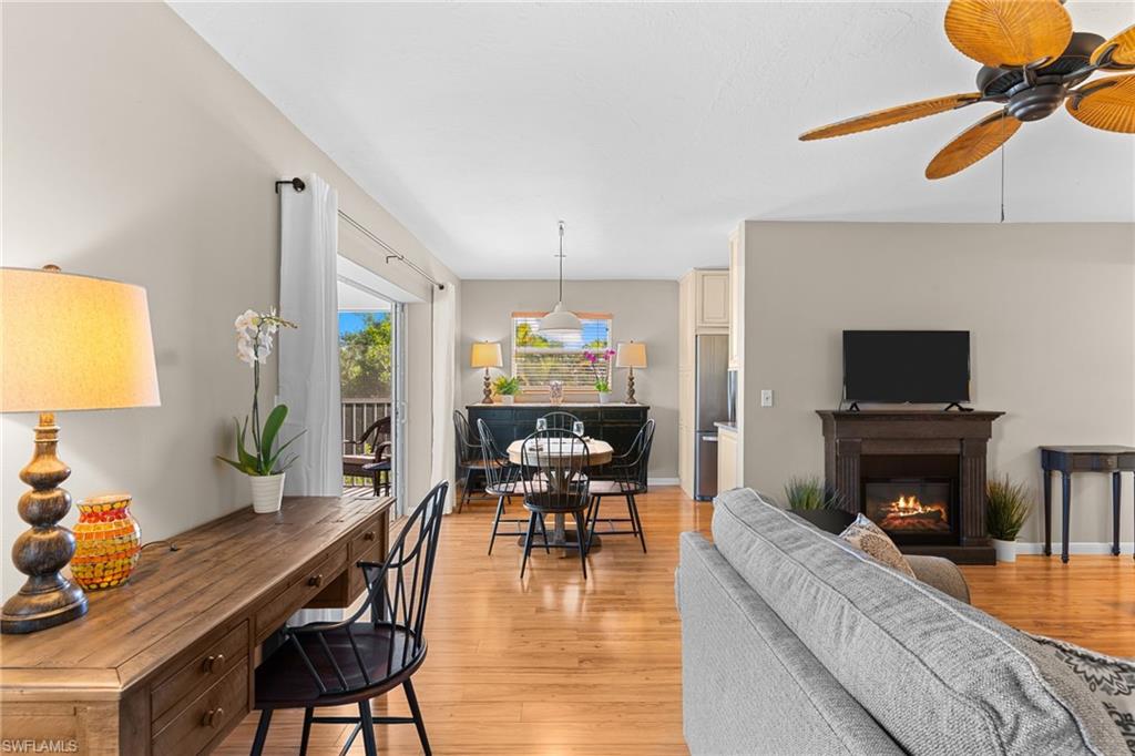 Living area featuring a glass covered fireplace, light wood-style floors, and a ceiling fan