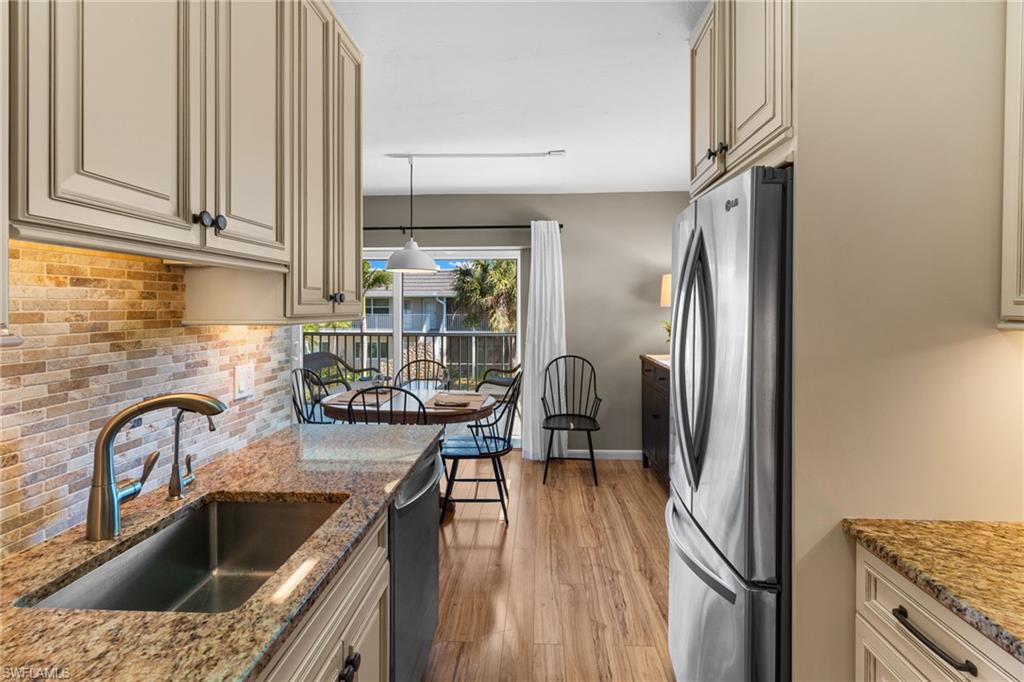 Kitchen with stainless steel appliances, light stone countertops, backsplash, and cream cabinetry