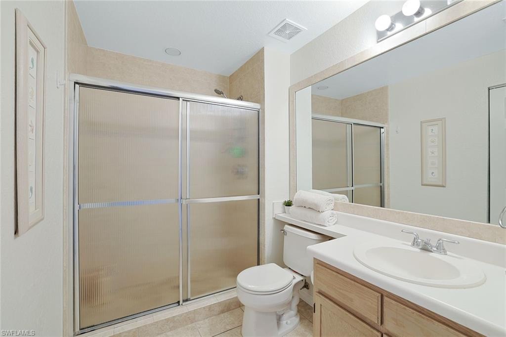 Full bath with a stall shower, vanity, and light tile patterned flooring
