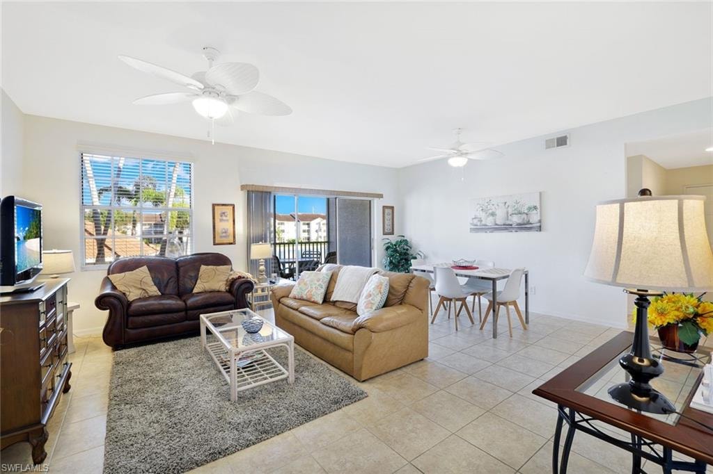 Living area featuring light tile patterned floors, healthy amount of natural light, and a ceiling fan