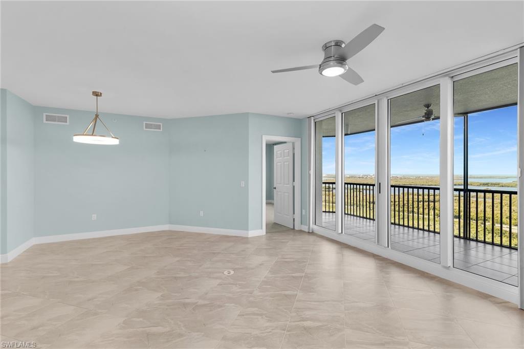 Unfurnished room with expansive windows and a ceiling fan