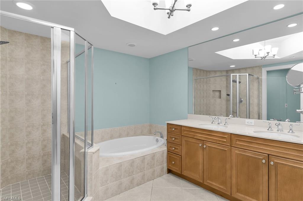Full bathroom featuring double vanity, recessed lighting, a bath, light tile patterned floors, and a chandelier