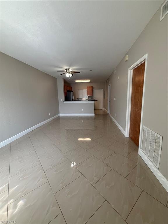 Unfurnished living room with ceiling fan and baseboards