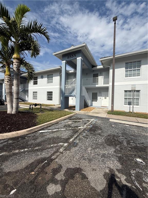 View of building exterior with stairway and uncovered parking