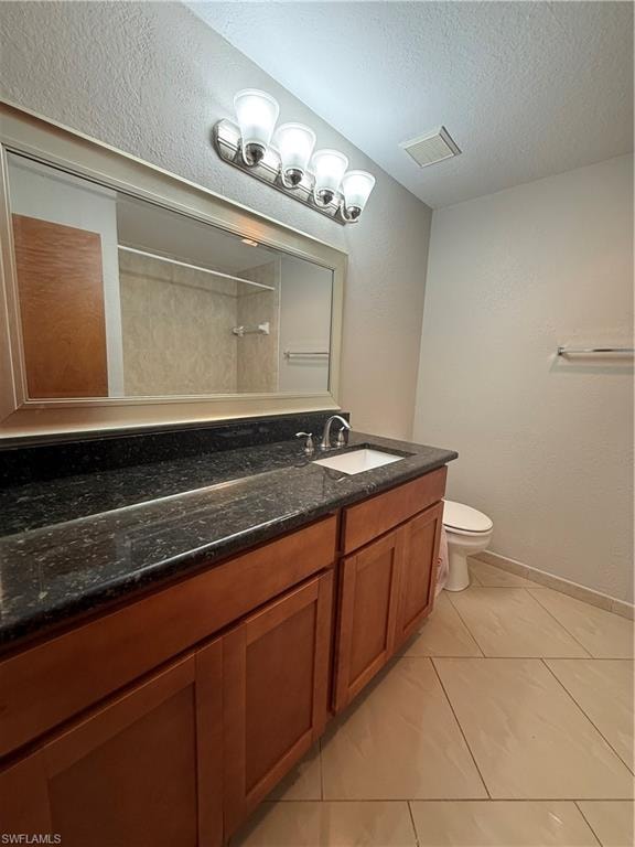 Full bathroom featuring vanity, a textured wall, light tile patterned flooring, a textured ceiling, and a shower