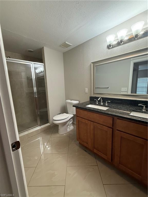 Full bath with double vanity, a stall shower, a textured ceiling, and a textured wall