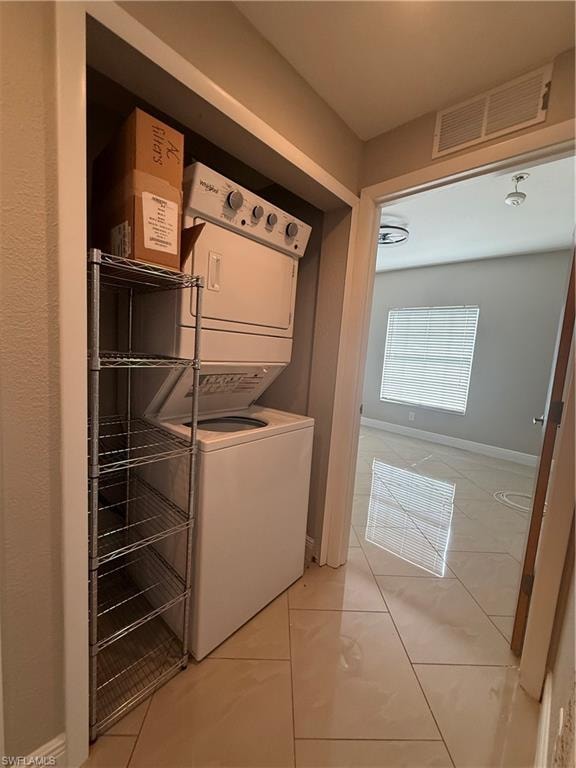 Laundry room featuring stacked washing machine and dryer and light tile patterned floors