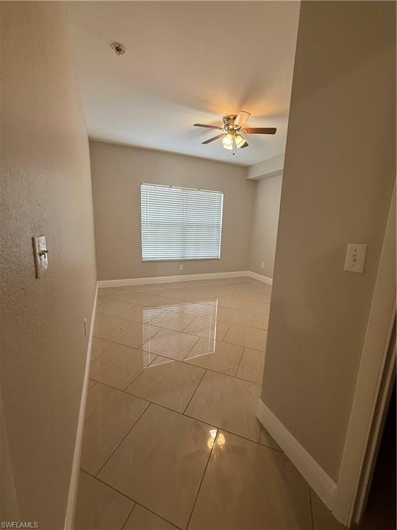 Empty room featuring a ceiling fan and light tile patterned flooring
