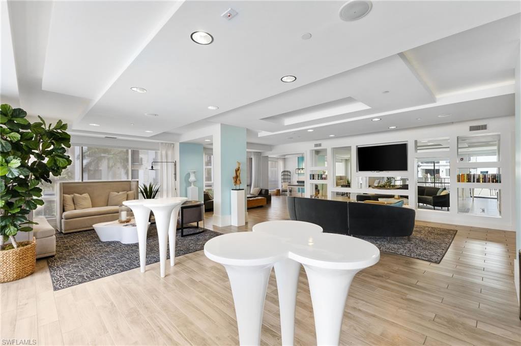 Living room featuring a tray ceiling, light wood-style flooring, and recessed lighting