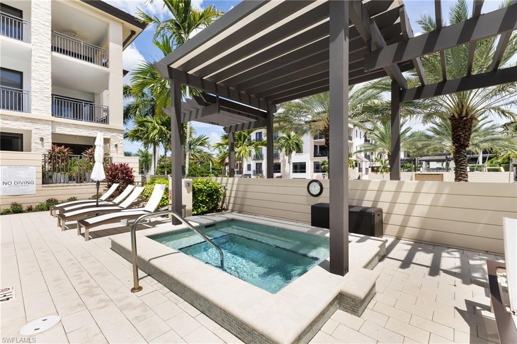 View of pool with a hot tub, a patio area, and a pergola