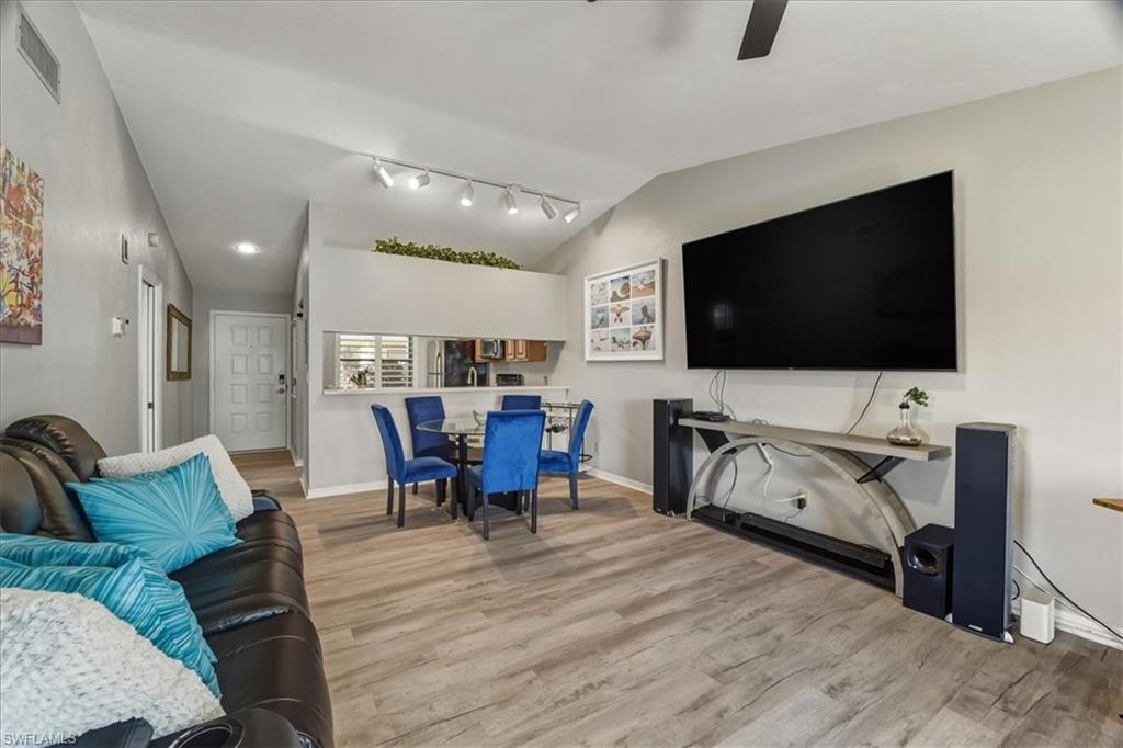 Living room featuring lofted ceiling, light wood finished floors, a ceiling fan, and rail lighting