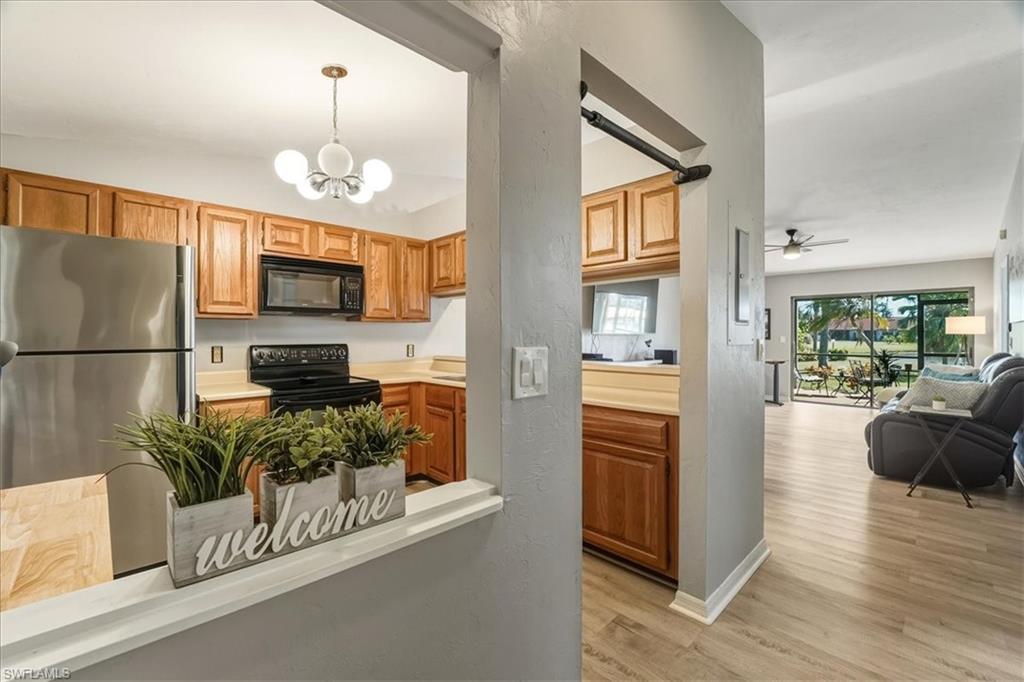 Kitchen with light countertops, black appliances, hanging light fixtures, light wood-type flooring, and a ceiling fan