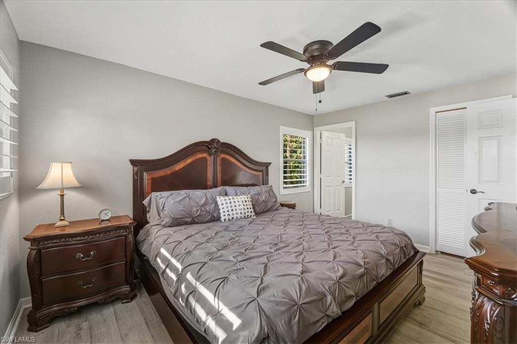 Bedroom with light wood finished floors, ceiling fan, and a closet