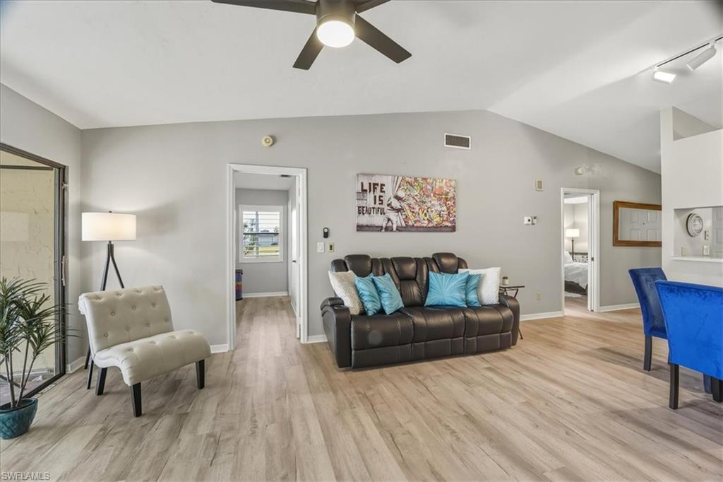 Living room with vaulted ceiling, a ceiling fan, light wood-style floors, and track lighting