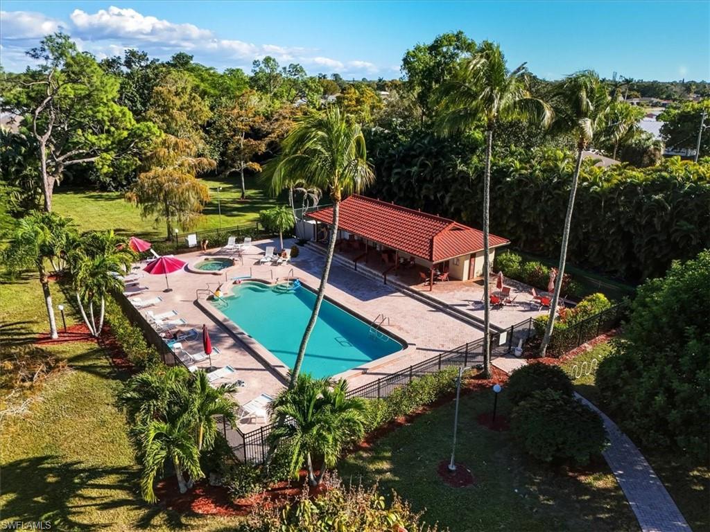 Community pool with a patio area, a community hot tub, and view of wooded area