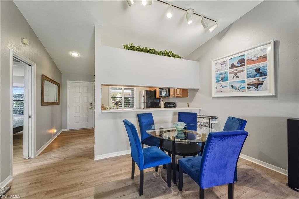 Dining area featuring light wood-style floors, lofted ceiling, and track lighting