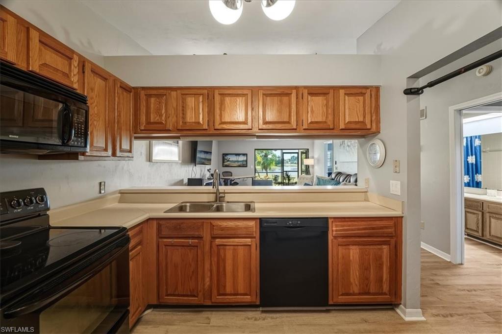 Kitchen with black appliances, brown cabinets, light countertops, and light wood finished floors