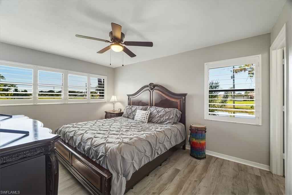 Bedroom with wood finished floors, ceiling fan, and multiple windows