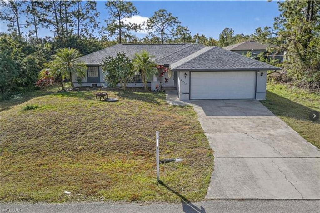Ranch-style home with a front yard, a garage, and concrete driveway