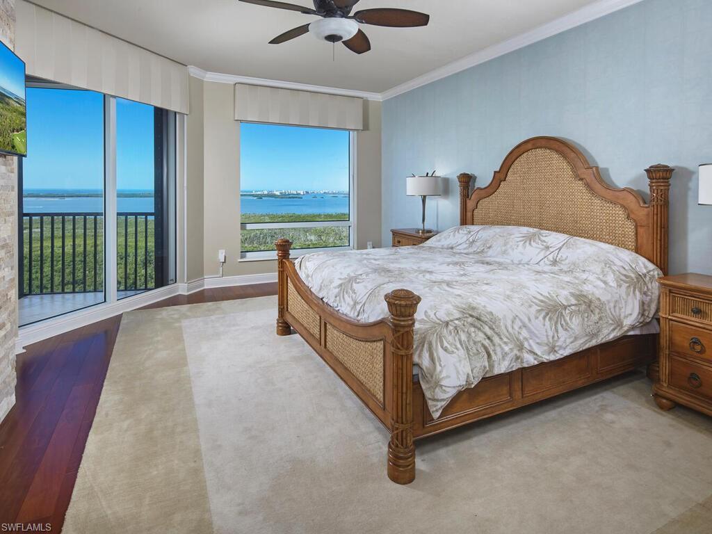 Bedroom featuring a water view, a ceiling fan, ornamental molding, and wood finished floors