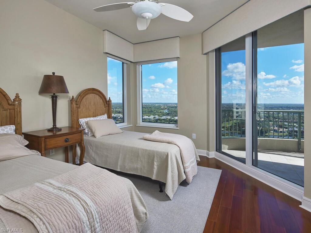 Bedroom with access to exterior, dark wood-style flooring, and a ceiling fan