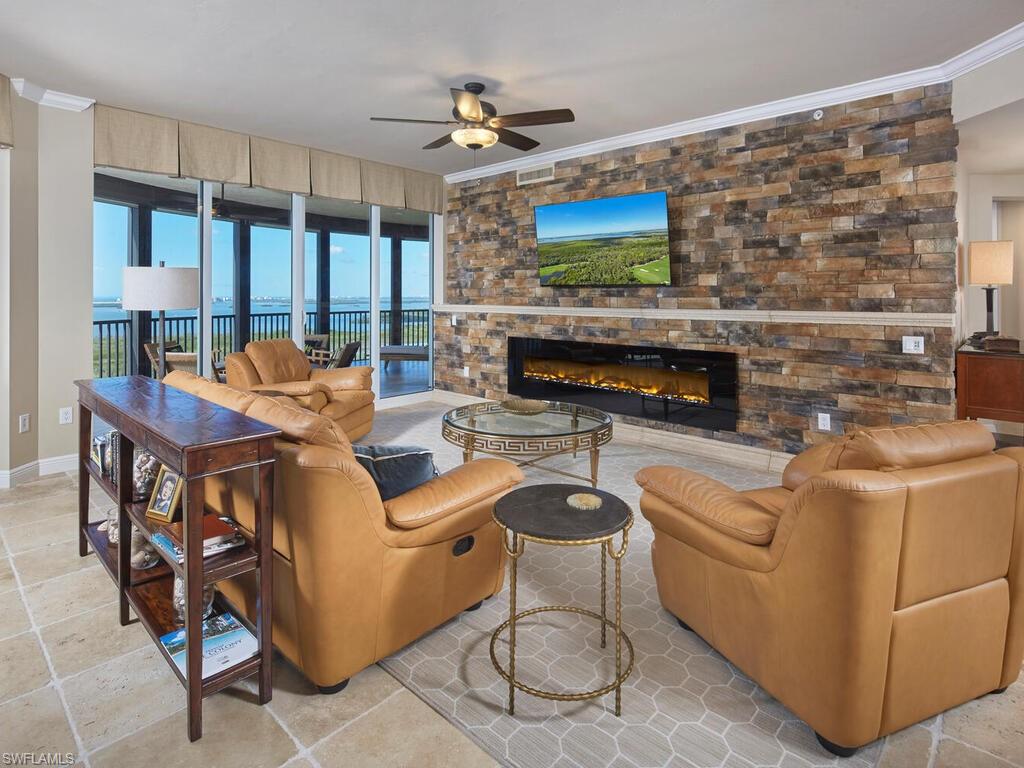Living area featuring a fireplace, crown molding, and a ceiling fan