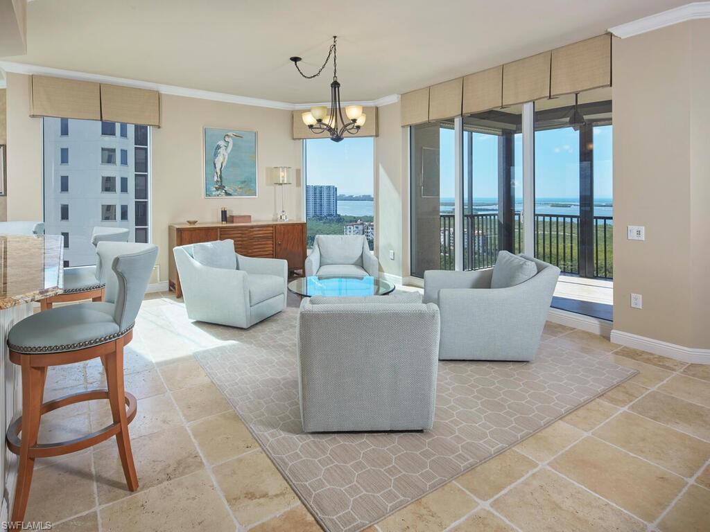 Living room featuring a chandelier, a water view, healthy amount of natural light, and crown molding