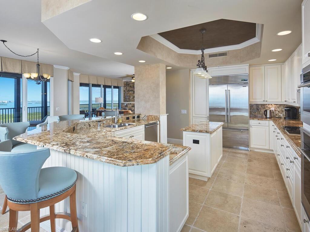 Kitchen featuring a center island, white cabinets, hanging light fixtures, light stone countertops, and a chandelier