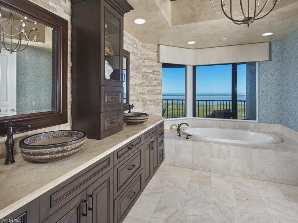 Full bathroom with a chandelier, a bath, double vanity, and a water view