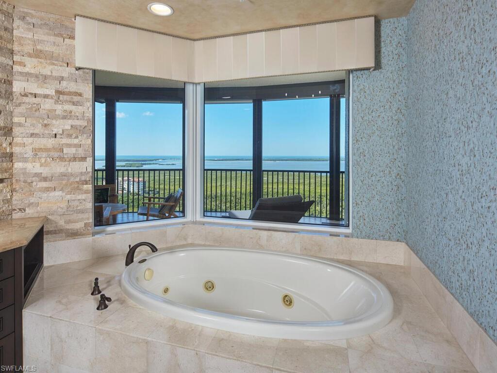 Bathroom featuring a whirlpool tub, healthy amount of natural light, wallpapered walls, and a water view