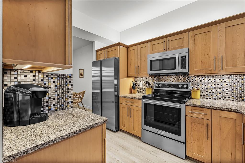 Kitchen featuring granite countertops, appliances with stainless steel finishes, tasteful backsplash