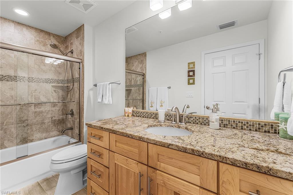 Guest full bathroom with vanity, bath / shower combo with glass door