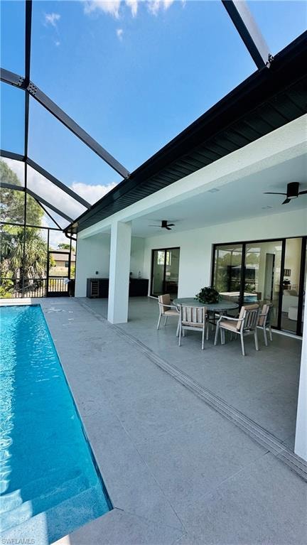 Screened-in outdoor living area featuring a rectangular pool with integrated steps, a spacious covered patio with ceiling fans, a full exterior kitchen, and multiple sliding glass door entries