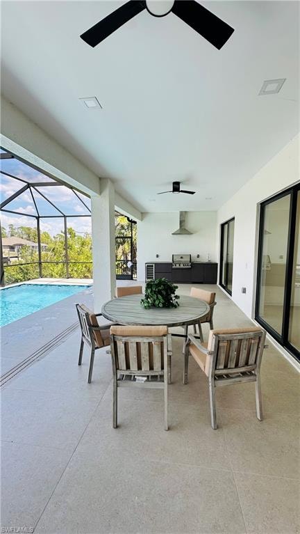 Expansive covered outdoor living area featuring a screened-in pool enclosure, an outdoor kitchen with stainless steel appliances and range hood, recessed lighting, and ceiling fans
