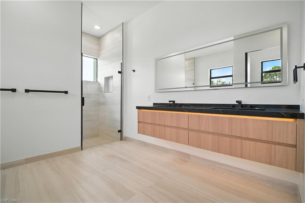 Full bathroom with double vanity, a shower stall, and plenty of natural light