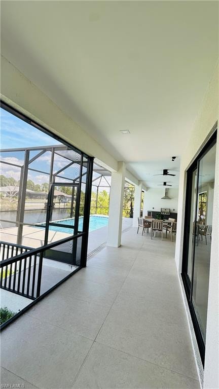 Expansive screened lanai featuring a swimming pool, tiled flooring, an outdoor kitchen with stainless steel appliances, and ceiling fans