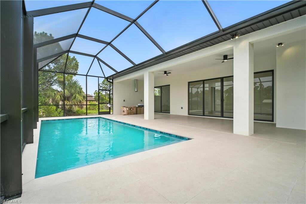 Outdoor pool featuring a sunroom, a patio area, and glass enclosure