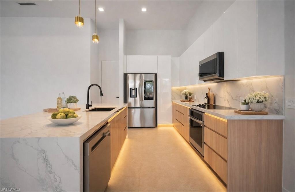 Kitchen with modern cabinets, pendant lighting, stainless steel appliances, light stone counters, and white cabinetry (Rendered photo)