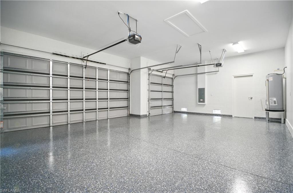 Garage with electric panel, electric water heater, and a garage door opener