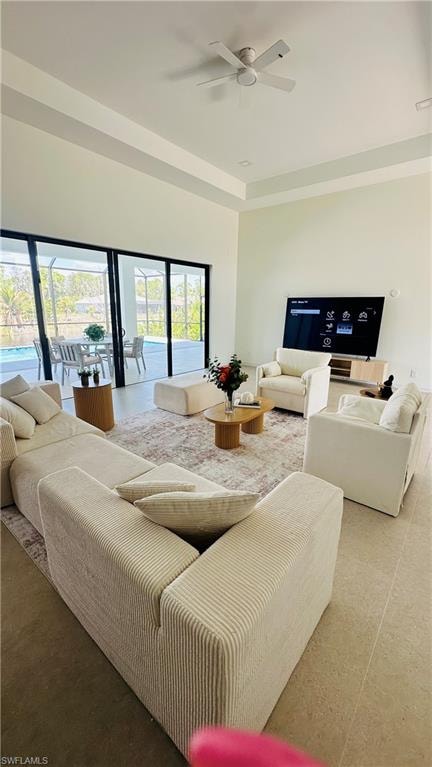 Open concept living space featuring tall ceilings with tray detailing, recessed lighting, and a ceiling fan