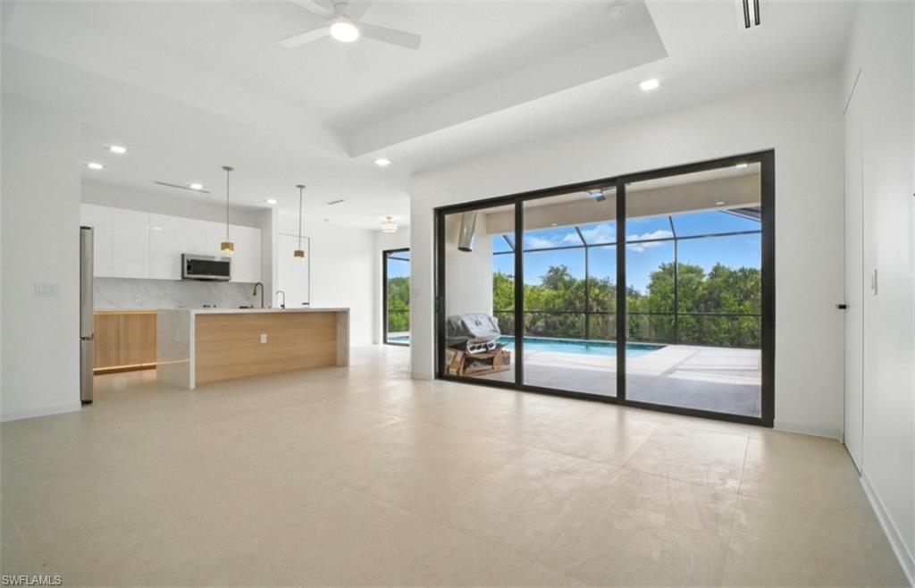 Unfurnished living room featuring a ceiling fan, a sunroom, a tray ceiling, concrete floors, and recessed lighting