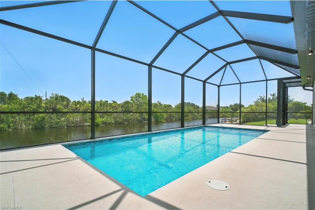 Outdoor pool with a sunroom, a lanai, a water view, and a patio area