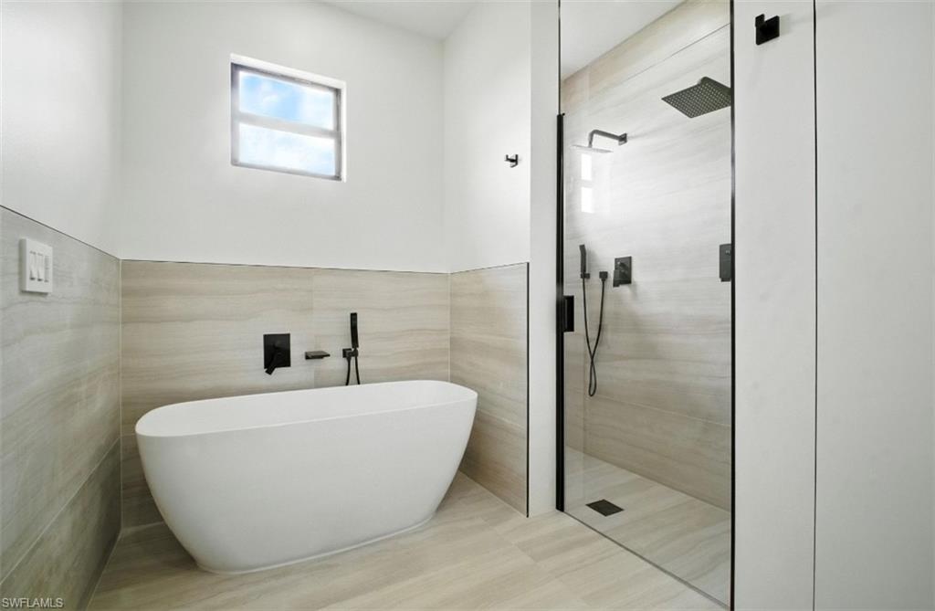 Full bath featuring a shower stall, a soaking tub, and tile walls