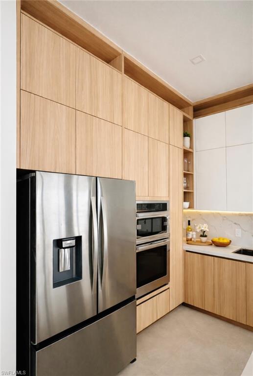 Kitchen with modern cabinets, stainless steel appliances, open shelves, two tone cabinetry, and decorative backsplash