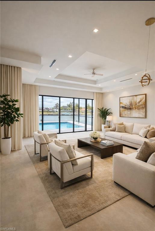 Living area featuring ceiling fan, recessed lighting, a tray ceiling, concrete flooring, and healthy amount of natural light
